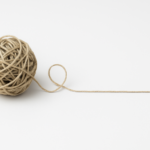 A ball of string unravelling into a single straight line on a clean white background — symbolising clarity emerging from complexity.